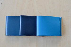 Simple Flap wallets in gray blue, navy and bright turquoise blue from architect Alice Park shown folded.