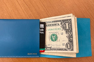 Simple Flap wallet in blue leather and white stitching from architect Alice Park shown open with bills and cards.