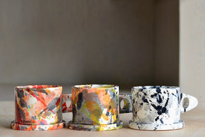 A selection of EXP standard splatter mugs by Peter Shire and Echo Park Pottery. The EXP standard splatter mug is a glazed ceramic mug with a triangular handle, made by utilizing slab construction that is hand rolled. Inspired by the techniques of Adrian Saxe and the paintings of Sam Francis, the mug was designed by Peter Shire for Echo Park Pottery. Peter is one of the original members of the Memphis Group, founded by Ettore Sottsas in Italy. Handmade in Echo Park, Los Angeles.