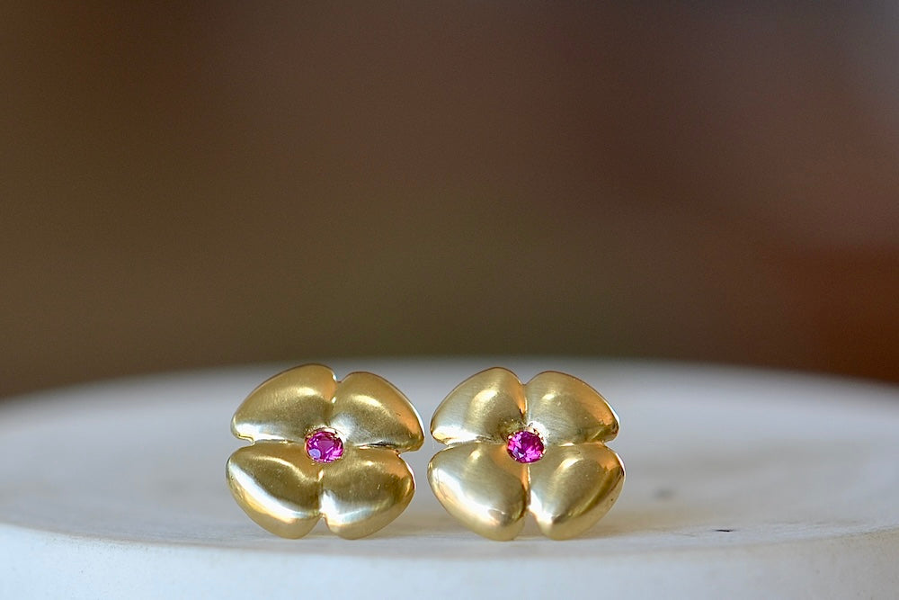 Large flower stud earring by Kaylin Hertel is a stud earring in the shape of a flower in 14k gold with a magenta hot pink sapphire in the center and post closure. 