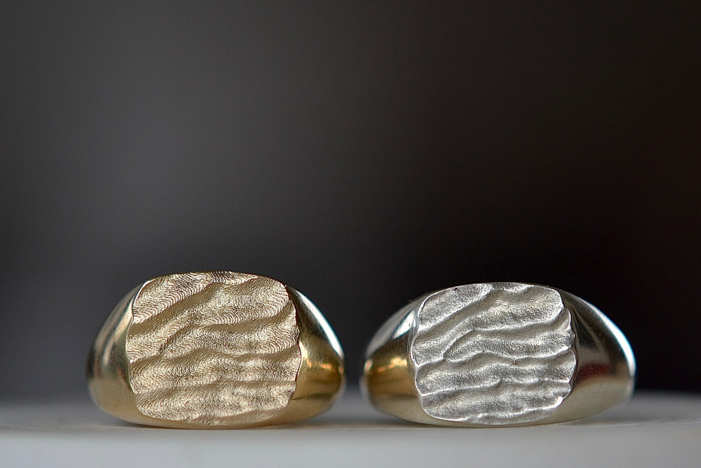 The Tidal Square Signet ring by Fraser Hamilton also known as the 'Tidal 10' is a square and solid modern signet ring in 9k yellow or white gold with polished band and matte face, featuring the maker's signature 'low tide' or 'ripple' texture on the face.