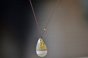 Agate and Citrine Pendant Necklace designed by Margaret Solow is a striped and smooth Agate stone slice accompanied by a smaller yellow and faceted citrine slice that is set in 14k gold with with a gold bead on the string makes this one of a kind organic pendant necklace.