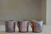 Selection of wood fired ceramic mugs by Lindsey Oesterritter. Wood ash in the kiln results in highly varying surfaces so each one unique,. As beautiful as they are functional. Sizes vary slightly, glazes considerably. These are part of our web selection and numbered 1, 2 and 3.