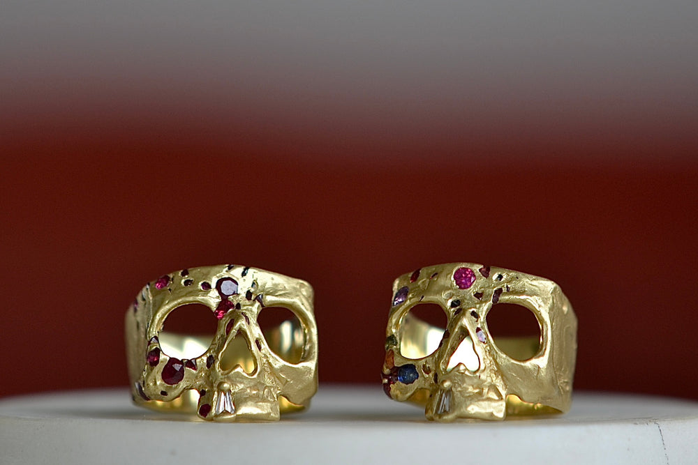 Polly Wales ruby confetti skull ring next to a rainbow confetti skull ring. 