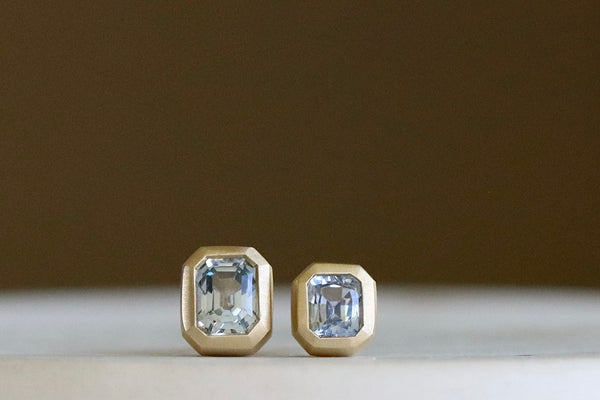 Bezel Set Asymmetrical Studs by Eliza eth Street Jewelry are a pair of asymmetrical square/rectangle, soft purpley blue and bezel set sapphire stud earrings with post closure in 14k yellow gold. Handmade in Los Angeles.