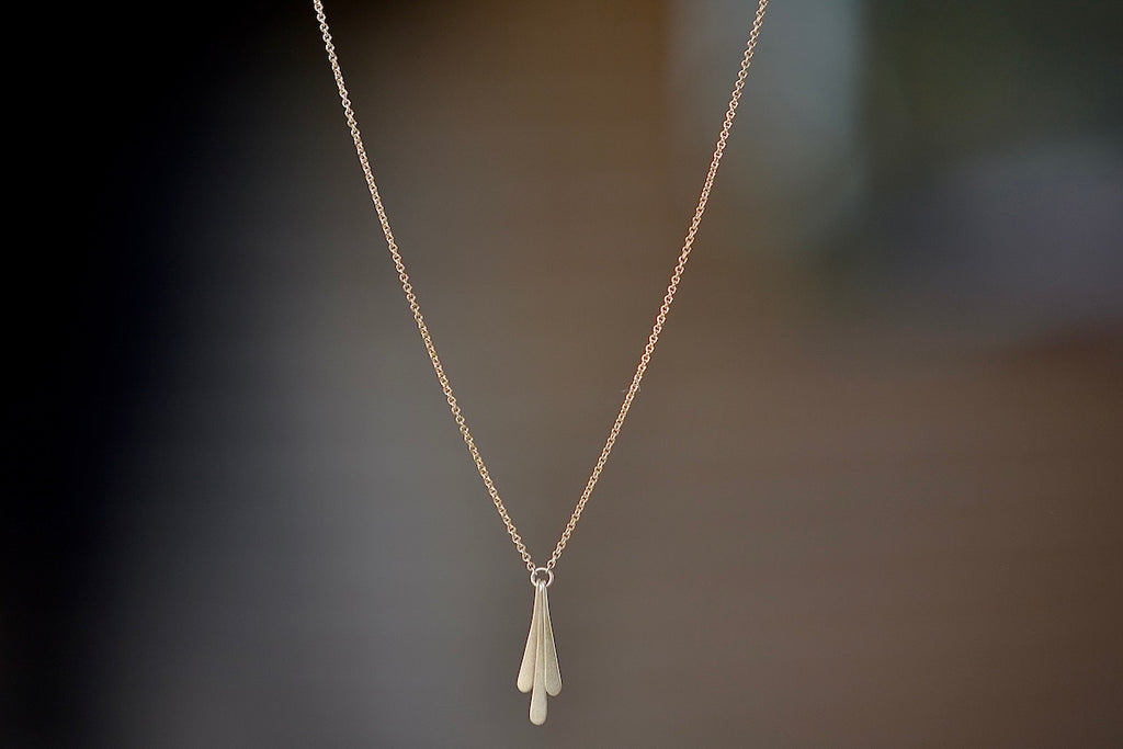Triple Fringe Necklace designed by Carla Caruso is made out of three elongated fringe drops of graduated length have been hand shaped, hammered and hung from a ring that is connected to a chain in 14k yellow gold and satin finish.