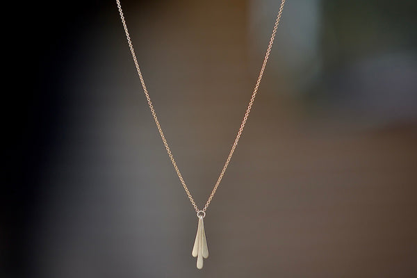 Triple Fringe Necklace designed by Carla Caruso is made out of three elongated fringe drops of graduated length have been hand shaped, hammered and hung from a ring that is connected to a chain in 14k yellow gold and satin finish.