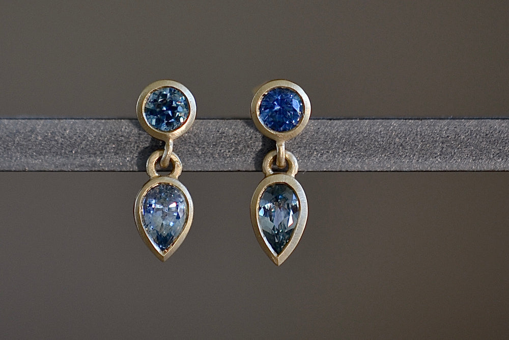 Montana Sapphire Duo Drop Earrings by Elizabeth Street are various shades of blue and round on top and pear cut on the bottom with post closure.