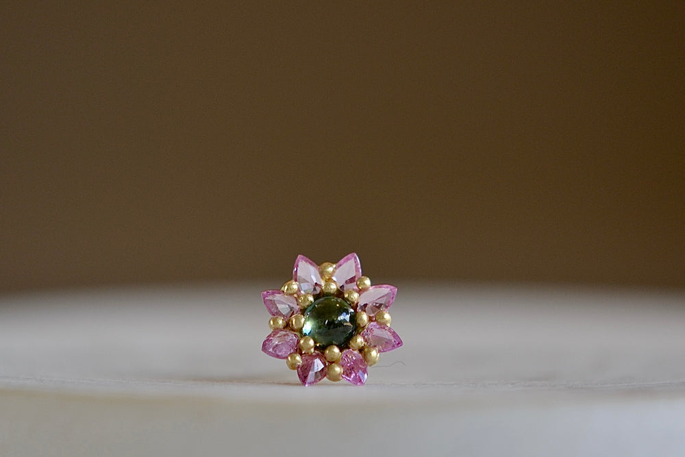 The Daisy stud by Polly Wales is a floral cluster made out of a half sphere in gold with a cabochon and encrusted inverted brilliant sapphires. We have one in green and pink.