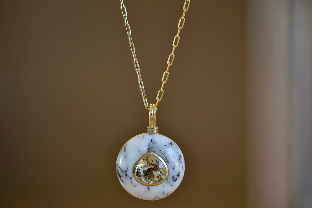 The large lollipop necklace in opalized dendrite by Retrouvai is a one of a kind pendant featuring a chunky and rounded stone face with a translucent center stone set on a generous chain. This one is opalized dentrite with a pear cut yellow tourmaline .