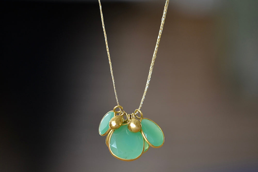 Colette Cluster Necklace in Chrysoprase with Gold Drops designed by Pippa Small is a Cluster of chrysoprase pendants bezel set stones in various sizes with two (2) 18k gold beads on 22" golden waxed cotton cord also known as the Flourishing Green necklace.