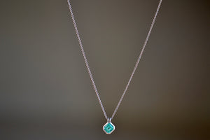 The duo bale emerald pendant in platinum by Elizabeth Street is a bezel set Colombian emerald set on its axis in a double bale and on a platinum chain.