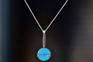  The signature Compass Pendant with Sleeping Beauty Turquoise and Tanzanite by Retrouvai is a pendant necklace with stone inlay that is accented with a center gem stone and a white diamond. The compass hangs from an elongated paperclip link accented with a second white diamond on 24" 14k yellow gold chain.