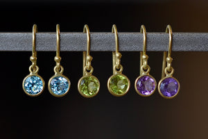 Tiny moon earrings by Tej Kothari are lightly faceted and translucent bezel set round and inverted stones on a gold ear wire hook in blue topaz, peridot or amethyst.
