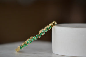 18k Zig Zag Firework Bangle in Emerald by Suzanne Kalan is a striking and prong set emerald baguettes on a trademarked zig zag fireworks setting with solid ends in 18k yellow gold form this flexible bangle cuff full of sparkle and texture. 1.5CT