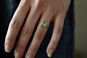 Wearing the The Elizabeth Street Jewelry Simple Emerald Band in size 6.5 is a bezel set (north/south) Colombian green emerald on a simple 14k satin yellow gold band. 