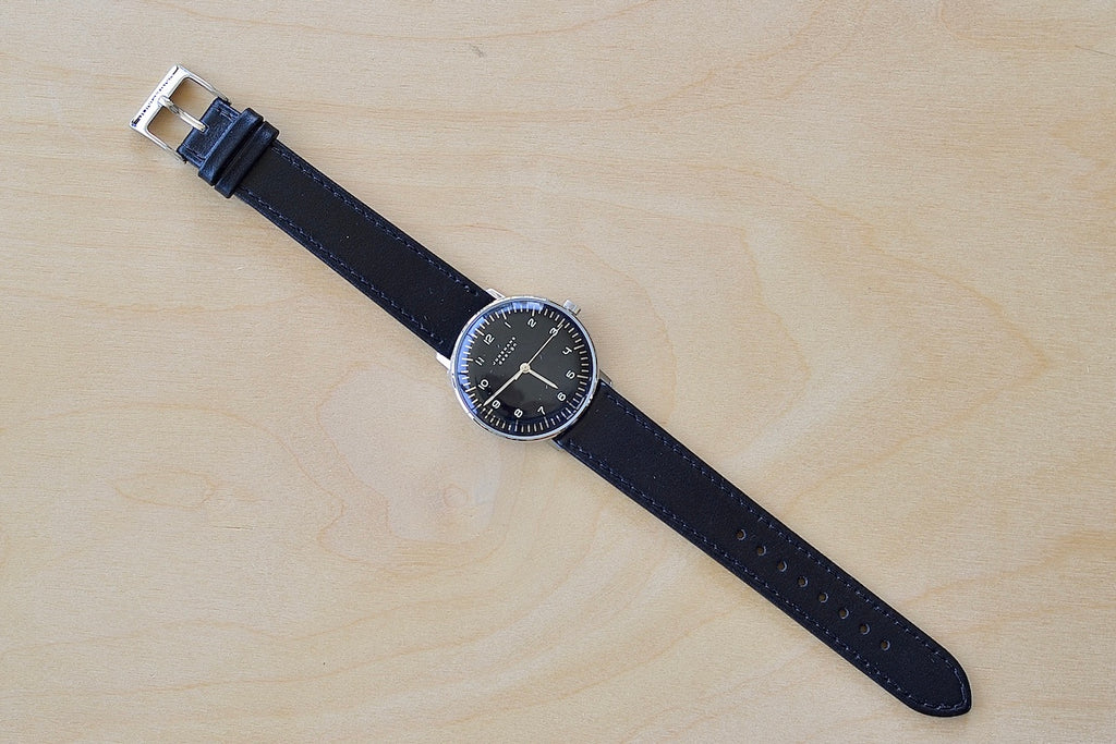 Full image of Max Bill 34mm Hand wound Watch Black Dial with Numbers designed for Junghans in 1961 and virtually unchanged. 34mm hand wound watch with black face and numbers with hand winding movement J805.1 (ETA 2801-2) and a sapphire crystal,  42 Hour Power Reserve in 316L stainless steel case available at OK..