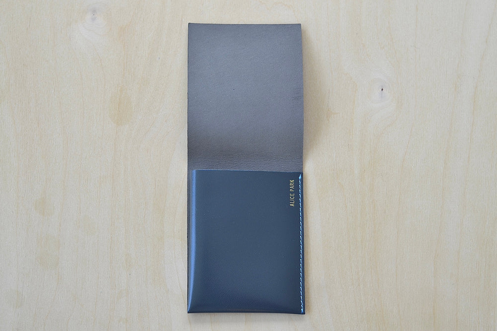 Inside of dark Gray Alice Park simple flap wallet with blue stitching.