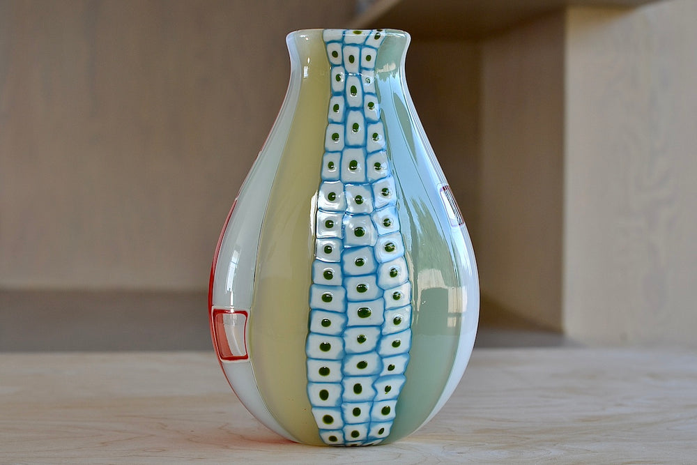 Spots on Robin Mix Medium Cane Vase Thaibo with Windows and Spots. Designed by Robin Mix in Tunebridge Vermont. Hand blown vase in multi colored stripes in onion, white, grey, taupe, orange-red and blue with windows on one side and green spots inside white squares on the other, using Italian techniques available at OK.