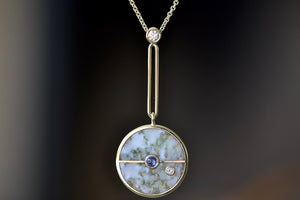 Close up of  The signature Compass Pendant with Green Agate and Tanzanite by Retrouvai is a pendant necklace with stone inlay that is accented with a center gem stone and a white diamond. 