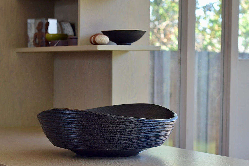 The Circle Factory Bowl in Black Oak with Ridges is a Large Circle turned wood bowl in Black Oak with ridged detail by George Peterson. Made in North Carolina. Food safe, but finish can be affected if in contact with anything acidic.