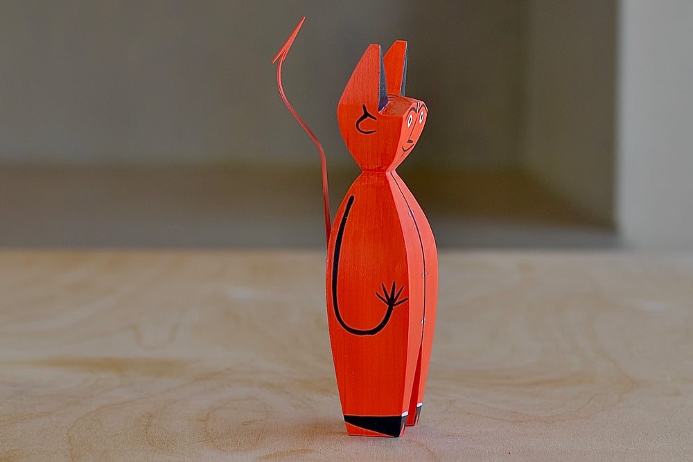 Side view of the The Wooden Little Devil is a bright red decorative figurine that is part of the Alexander Girard doll collection.