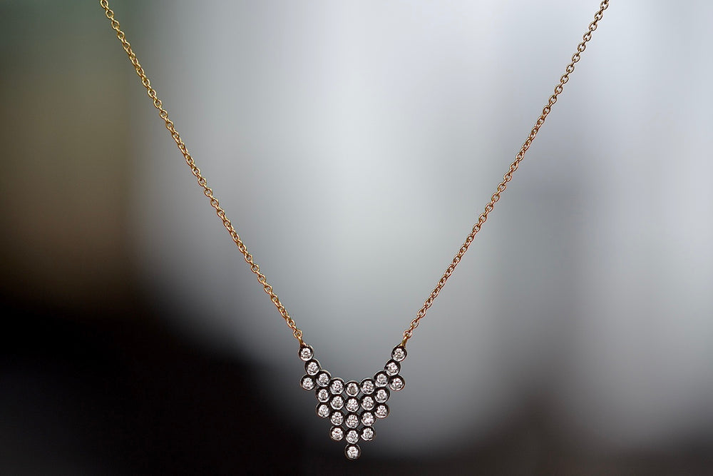 Close up of Charnières Pétale Pendant Necklace by Yannis Sergakis is twenty-Five (25) rhodium plated round cut diamonds that form a triangular pendant on an 18k gold chain.