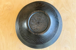 Bottom of circle factory bowl in black oak with ridges.