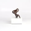 Anne Ricketts Repose Sculpture of modern woman in brass on white background. Muse.