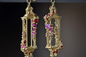 Close up detail of Polly Wales Jade Terrace Pagoda Earrings 18K yellow recycled gold pagoda forms hanging from a bird stud encrusted with a pearl pink and orange sapphire sapphires. Cast not set.