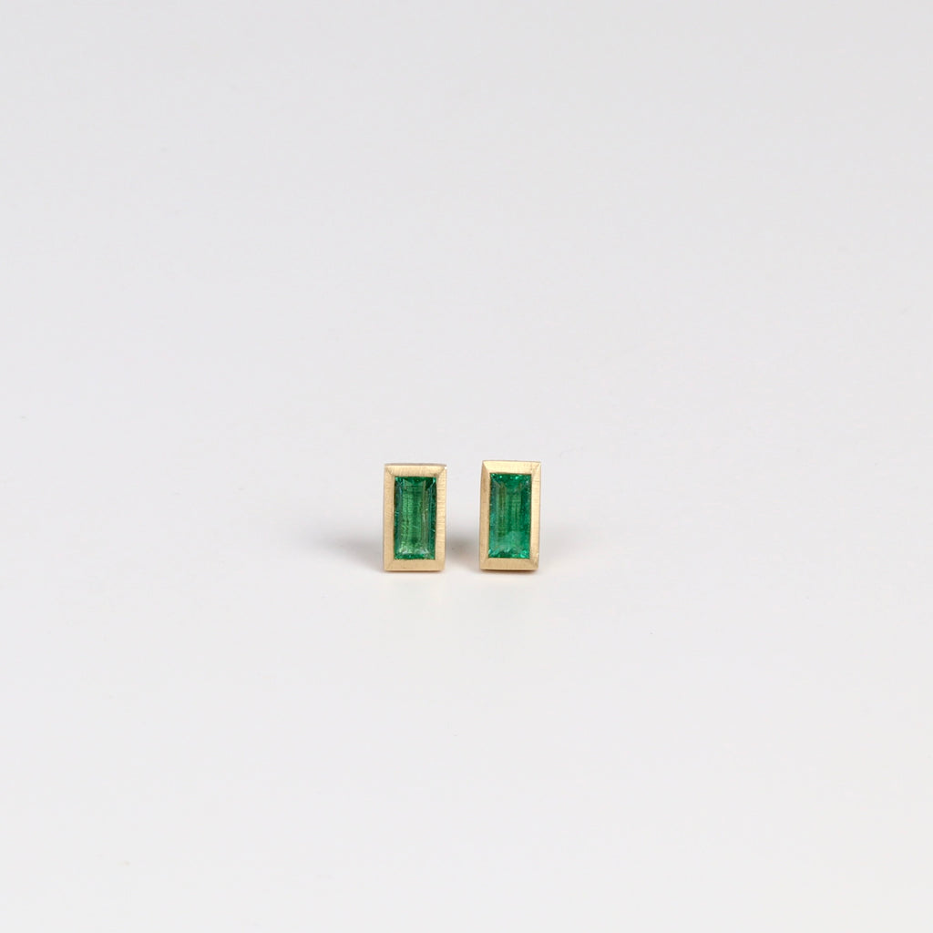Front view of Elongated Emerald stud earrings with Zambian stone and bezel set in satin finish 14k yellow gold with post closure.