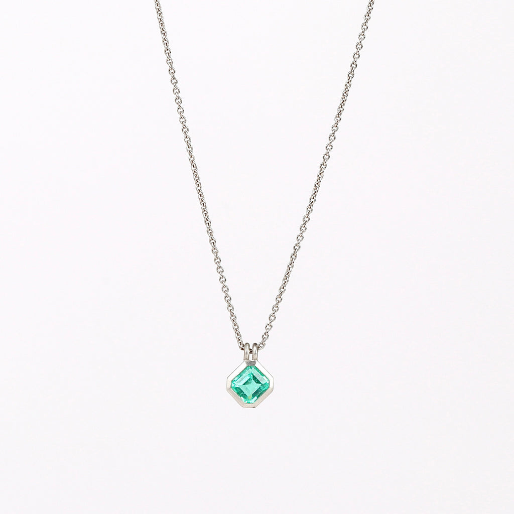 The duo bale emerald pendant in platinum by Elizabeth Street with platinum chain on white background.