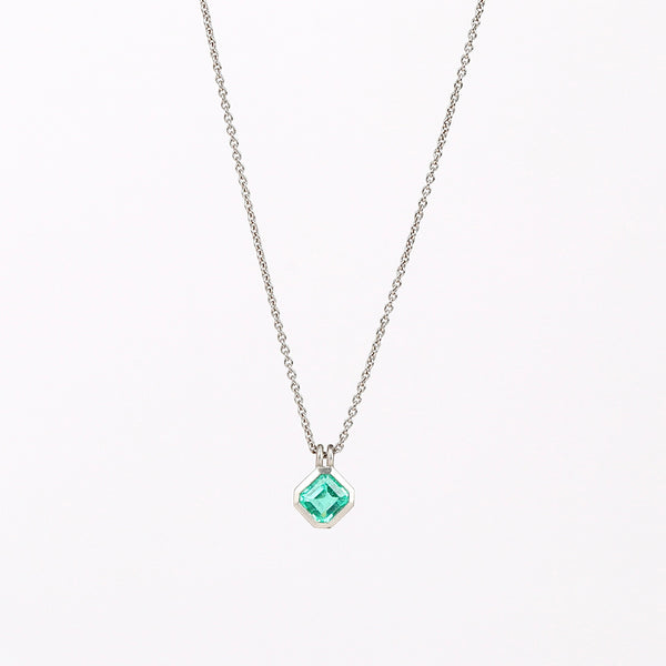 The duo bale emerald pendant in platinum by Elizabeth Street with platinum chain on white background.