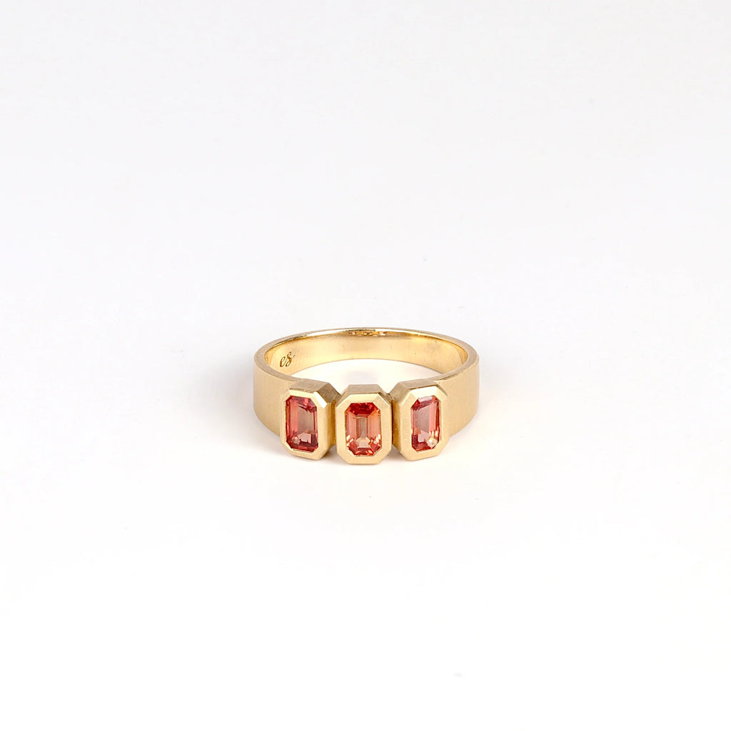 Triple Sapphire Band by Elizabeth Street Jewelry on white background. Made out of three rose sappires bezel set into a simple satin brushed and tapered band in 14k yellow gold. Handmade in Los Angeles.