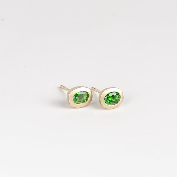 Side view of Tsavorite Oval Studs by Elizabeth Street Jewelry are a pair of heavy bezel and oval Tsavorite garnet .73tcw studs with post closure in 14k yellow gold. Handmade in Los Angeles