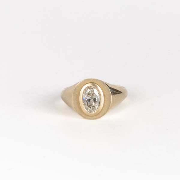 Front of Oval Signet by Elizabeth Street Jewelry. A bezel set oval lab grown diamond in a multi surface circle signet ring on a tapered 14k yellow gold band. Handmade in Los Angeles.