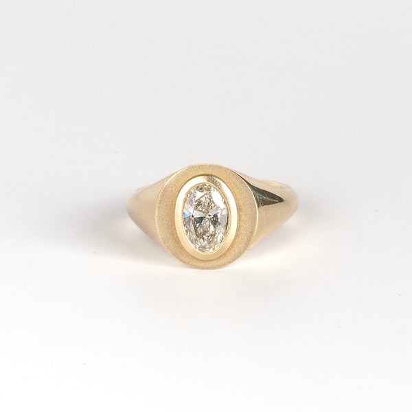 Front of Oval Signet by Elizabeth Street Jewelry. A bezel set oval lab grown diamond in a multi surface circle signet ring on a tapered 14k yellow gold band. Handmade in Los Angeles.