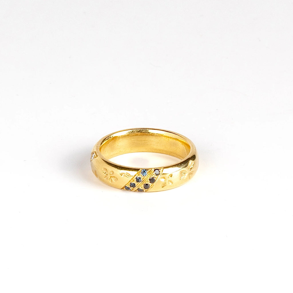 Kaylin Hertel Striped Petal Print Band in Blue is a thick comfort fit band encircled by hand carved petal print and adorned with 3 pave stripes in diamond and dark blue sapphires, white and black diamonds on white background.