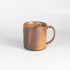 A wood fired  ceramic mug by master of wood fired ceramics, Lindsay Oesterritter. Wood ash in the kiln results in highly varying surfaces so each mug is unique,. As beautiful as they are functional. Sizes vary slightly, glazes considerably. One of a kind.