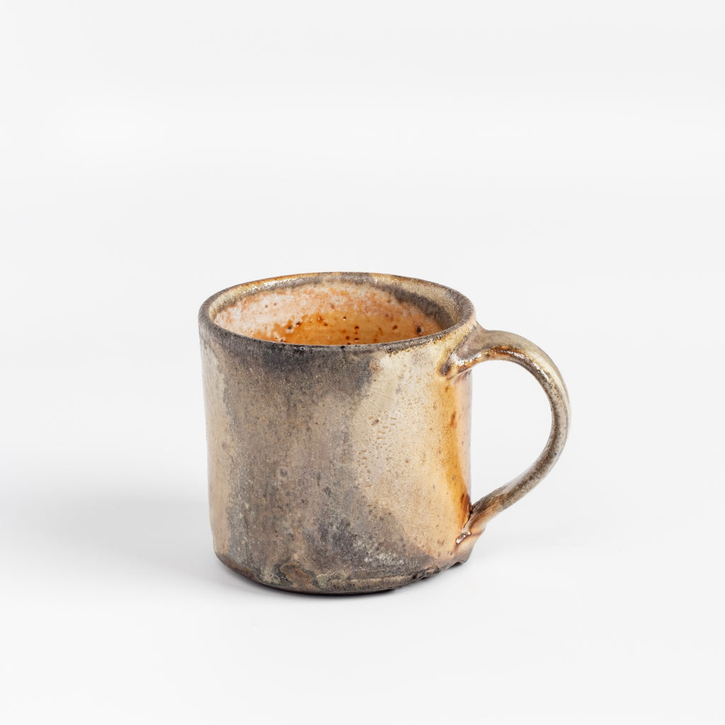 A wood fired  ceramic mug by master of wood fired ceramics, Lindsay Oesterritter. Wood ash in the kiln results in highly varying surfaces so each mug is unique,. As beautiful as they are functional. Sizes vary slightly, glazes considerably. One of a kind.