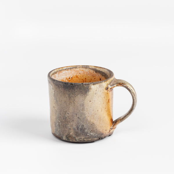 A wood fired  ceramic mug by master of wood fired ceramics, Lindsay Oesterritter. Wood ash in the kiln results in highly varying surfaces so each mug is unique,. As beautiful as they are functional. Sizes vary slightly, glazes considerably. One of a kind.