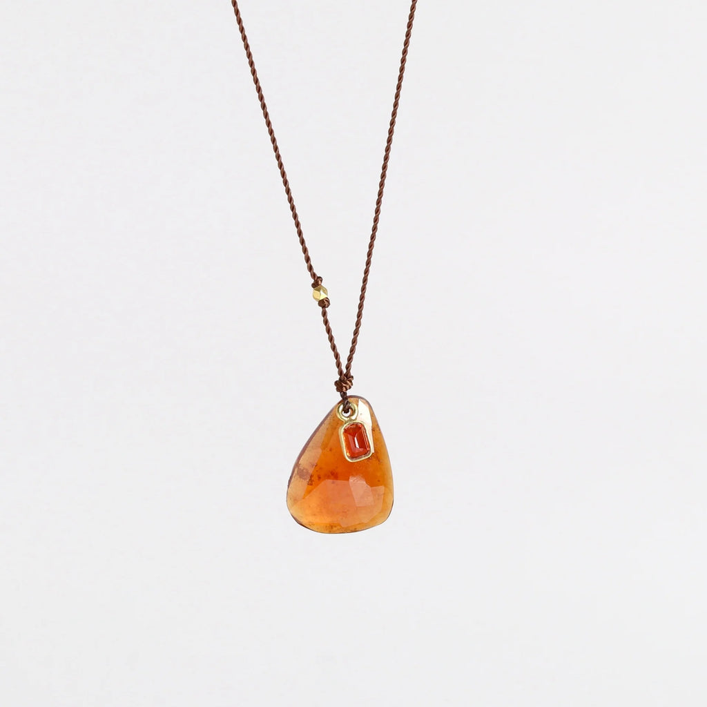 Hessonite and Sapphire Pendant Necklace designed by Margaret Solow is a A faceted Hessonite stone slice accompanied by a smaller orange and faceted sapphire slice of which the smaller is set in 18k gold with with a gold bead on the string makes this one of a kind organic pendant necklace.