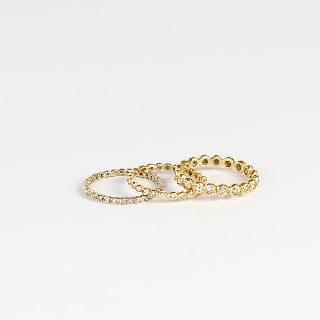 1mm, 1.25mm and 3mm thick diamond porch bands by Marian Maurer on white background. These wedding bands are made out of bezel set round diamonds.