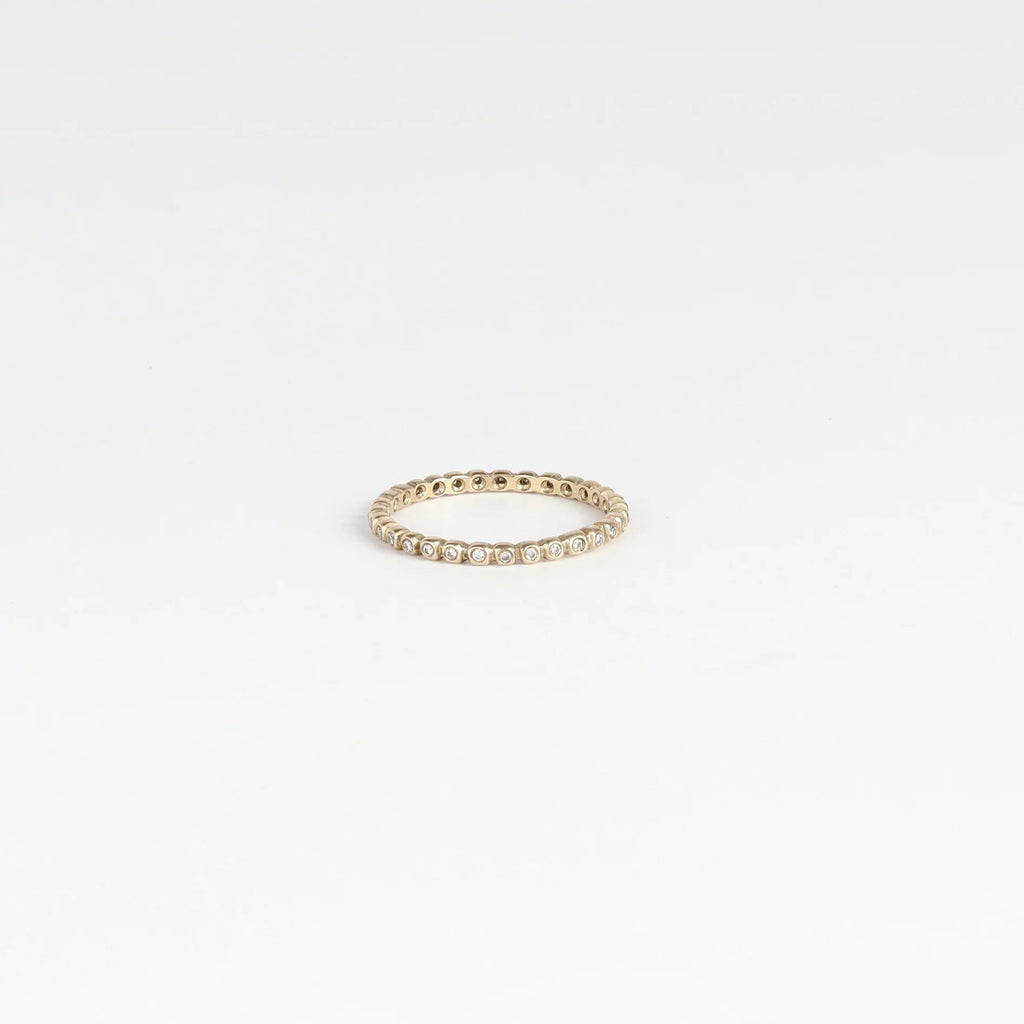 1mm thick diamond porch band by Marian Maurer on white background. This is a wedding band in bezel set round diamonds.