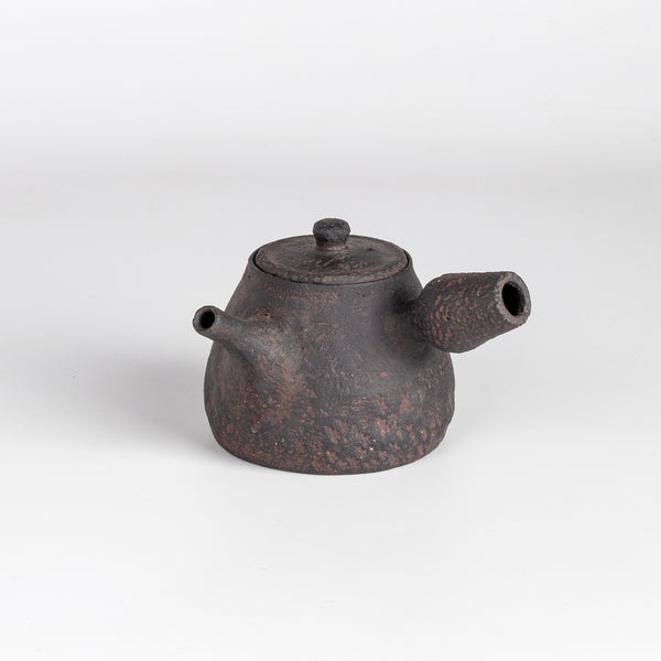 Dark brown Kyusu teapot D by Muzuri ware is a composed ceramic teapot, utilizing mostly black stained London clay, textured and inlayed with costal wild Cornish clay. Some are inlayed with black iron oxide. Wheel thrown and assembled with interior holes to work with a variety of tea leaves by Kyriacos Mouzouris in London UK.