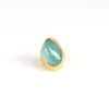 The Aquamarine Tibetan Ring designed by Pippa Small Jewellery is a smooth tumbled aquamarine that is encased in 22k gold on white background.