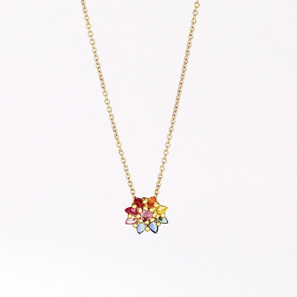 Daisy necklace in Rainbow by Polly Wales with pink cabochon center and rainbow  inverted and encrusted brilliant sapphires in hot pink, pink, lilac, blue, orange, green, and yellow. 