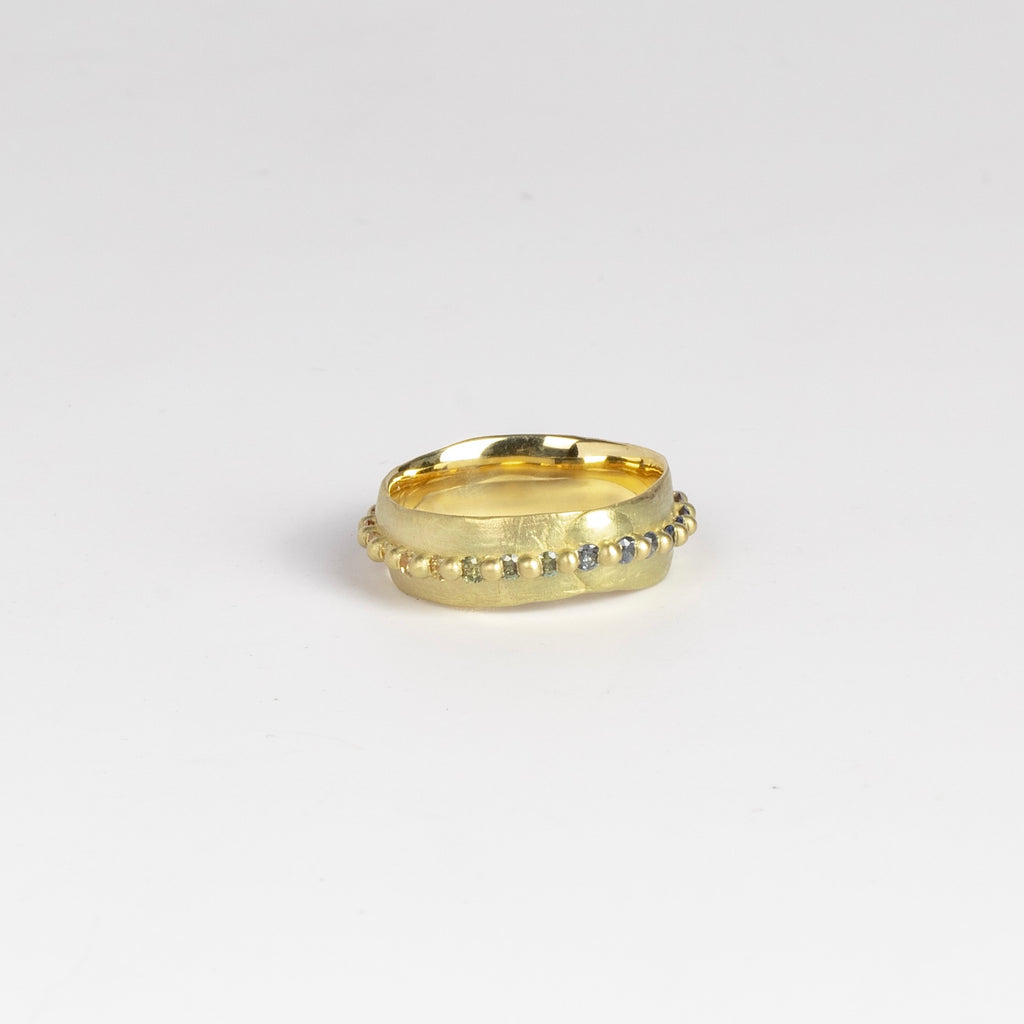 Nina ring in Rainbow by Polly Wales is a pinch band, showing green and blue sapphires.