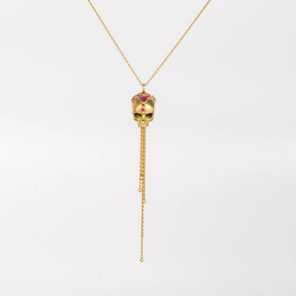 Polly Wales Forbidden Skull Necklace in 18k yellow recycled gold with pink fuchsia sapphires on an extra (XL) long chain forms this pendant necklace on white background.