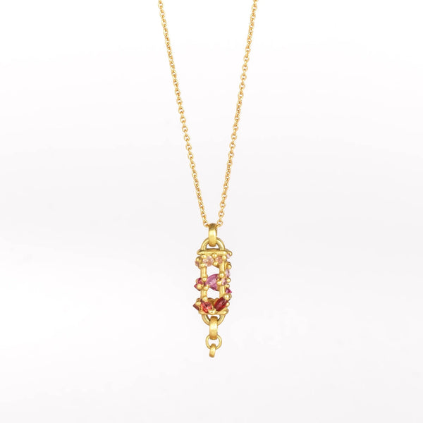 Vertical Fontaine Bar Necklace in Plum Blossom by Polly Wales is an oval and three dimensional bar in 18K yellow gold holds a vine of encrusted and inverted sapphires in pink, fuchsia and red that have been cast and are accompanied by matte gold dots. The bar hangs on a beautiful gold chain and bale. Shown on white background.